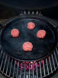 Gietijzeren plancha met hamburger erin.